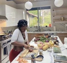 a woman cutting up food on top of a kitchen counter