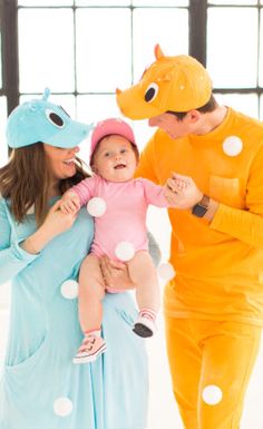 two adults and a baby dressed up in animal onesuits, one holding the child