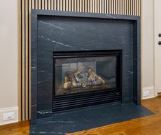 a fireplace in a living room with wood flooring and striped wall paper on the walls