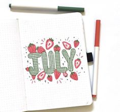 an open notebook with the word july written in cursive writing and strawberries