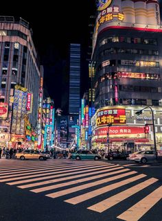 a city street filled with lots of tall buildings and neon signs at night time,