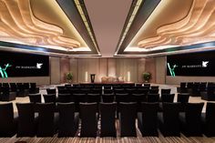 an empty conference room with black chairs and large screens on the wall above them that are lit up