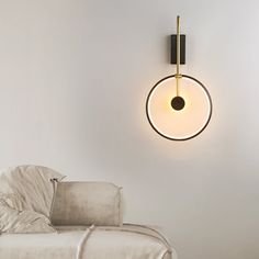 a living room with a white couch and a wall light in the shape of a circle