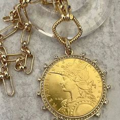 Gold Coin Necklace Beautiful reproduction vintage coin pendant, French Madagascar coin in a bezel with cubic zirconia stones. The bale attached to the coin is also encrusted with CZ stones. The coin is 22k gold plated and elegantly hangs from a multi link gold plated brass chain and a rope design spring lock clasp. The spring lock closure not only makes it easy to open and close the necklace for those with difficulty but adds to the creativity of the jewelry piece. Please see photograph of how t Luxury Symbolic Coin Necklace With Coin Pendant, Luxury Coin Necklace With Large Amulet Pendant, Luxury Brass Coin Necklace With Round Pendant, Luxury Amulet Charm Necklace With Coin Pendant, Luxury Amulet Style Charm Necklace With Coin Pendant, Luxury Gold-tone Chain Necklace With Coin Pendant, Luxury Coin Pendant Charm Necklace For Women, Luxury Gold Coin Necklace With Locket, Luxury Gold-tone Necklace With Coin Pendant