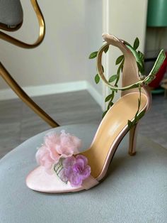 Step into a garden of elegance with the Claire Floral Heels. These stunning heels feature a delicate pink base adorned with intricate floral details, making them the perfect accessory for a romantic and feminine look. The ankle strap is beautifully decorated with green leaf accents, adding a whimsical touch that complements the soft, ethereal flowers on the toe. Crafted with a satin finish, the Claire Floral Heels offer a luxurious feel and a comfortable fit. The open-toe design showcases your p Pink Wedding Heels, Ethereal Flowers, Stunning Heels, Formal Accessories, Pink High Heels, Floral Heels, Floral Sandals, Heels Outfits, Floral Shoes