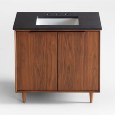 a wooden cabinet with a white sink and black counter top on it's side