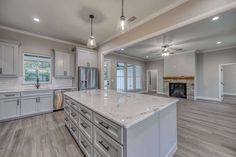 a large kitchen with white cabinets and marble counter tops, along with an island in the middle