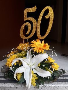 there is a 50th birthday cake with flowers on the table and candles in the shape of 50