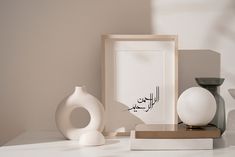 a white vase sitting on top of a table next to a framed photo and other items