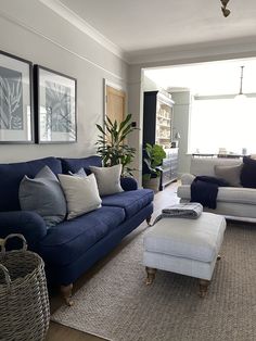 a living room with blue couches, white chairs and a rug on the floor