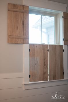 an open window with wooden shutters in a white wall and wood paneling on the outside