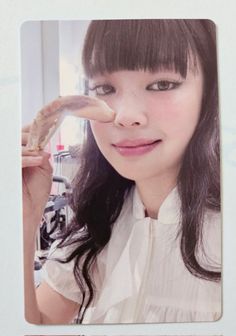 a woman with long black hair holding a banana in front of her face