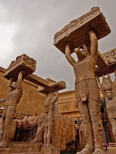 an image of statues in the middle of a building with people standing around them and one holding a box on his head