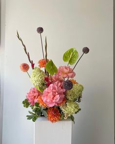 a white vase filled with lots of colorful flowers