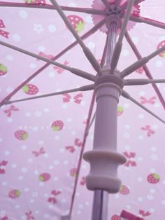 an open umbrella with pink and white polka dot designs on it's sides, in front of a wallpapered background