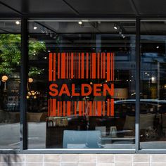 the reflection of a barcode sign in a store window's glass door that says, salen