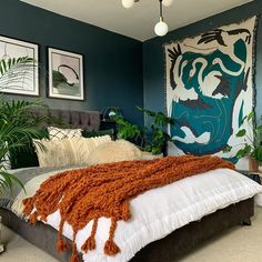 a bedroom with blue walls and white bedding, plants on the side of the bed