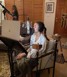 a woman sitting in front of a laptop computer on top of a chair next to a microphone