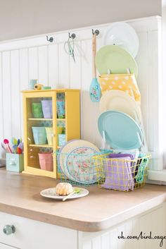 a kitchen counter with plates and bowls on it, next to a cabinet filled with dishes