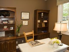 a room with a table, bookshelf and lamp