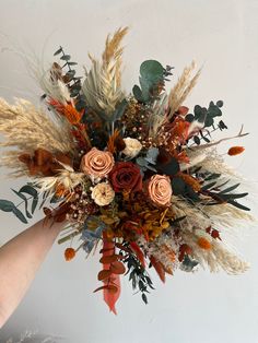 a person holding a bouquet of dried flowers