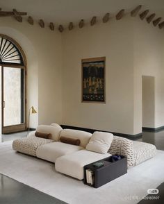 a living room with a large white couch in front of an open door and a painting on the wall