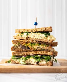 a stack of sandwiches sitting on top of a wooden cutting board