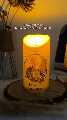 a lit candle with an image of a man on it and the words, if bright tears, but also peace to their heart