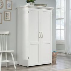 a white armoire next to a chair in a room