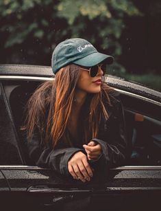 a woman sitting in the back of a car wearing sunglasses and a hat on her head