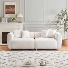 a living room with a white couch and coffee table in front of a fire place