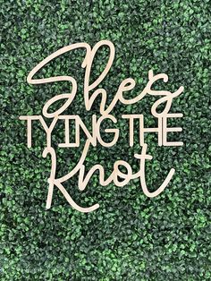 the words she's tying the knott are cut out from wood and placed on top of a green wall