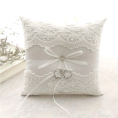 a white ring pillow with two wedding rings tied to the front and back of it