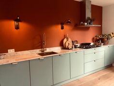 a kitchen with orange walls and white counter tops is pictured in this image, there are two lights on the wall above the sink