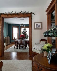 a living room and dining room are decorated with christmas greenery on the mantles