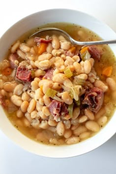 a bowl of ham and white bean soup with a spoon in it, on top of a table