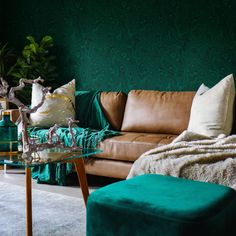 a living room with green walls and leather furniture in the corner, along with a glass coffee table