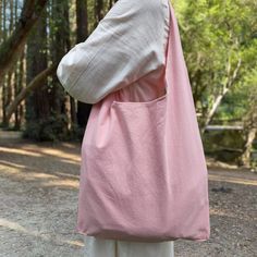 a woman carrying a pink bag on her back with trees in the background at daytime