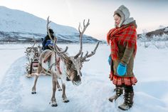 a woman standing next to a reindeer in the snow