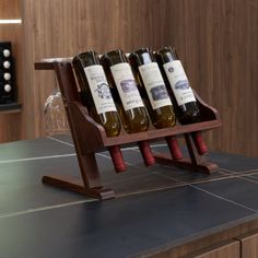 four bottles of wine are sitting on a wooden stand in front of a kitchen counter