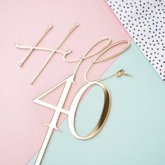 a pink and blue table with a gold cake topper that says happy forty birthday