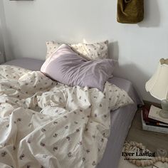 an unmade bed with white sheets and pink pillows