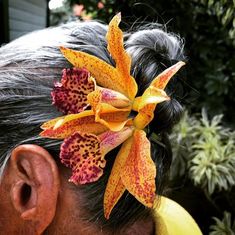 a close up of a person with a flower in her hair and an ear ring