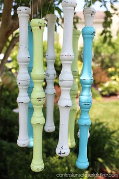 an assortment of colorful painted candles hanging from a tree in front of some bushes and trees