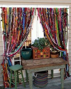 a wooden table sitting next to a window covered in colorful scarves