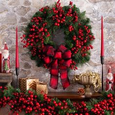 a christmas wreath on a mantle with candles and other holiday decorations in front of it