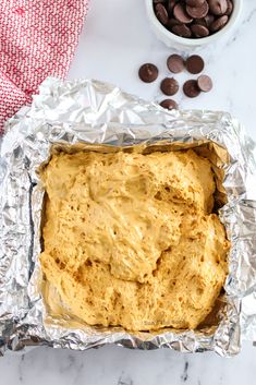 an uncooked loaf of bread sitting on top of tin foil next to chocolate chips