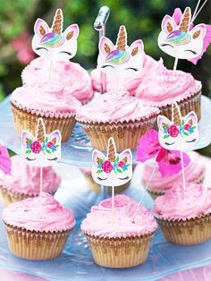 cupcakes with pink frosting and unicorn ears on top are sitting on a blue plate