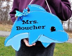 a person holding a sign that says mrs boucher with a dolphin on it