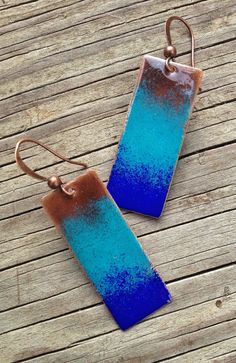 two rectangular blue and brown earrings on wooden planks